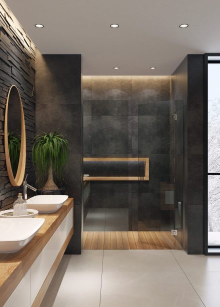 contemporary minimalist bathroom with two round mirrors and wooden frame.
natural stacked black matte stone wall with large black matte tiles.
two rectangular white wash basins are on top of the long wooden cabinet with
white doors. large white matte floor tiles. wooden floor tiles in walk-in shower.
ceiling strip cove lighting with embedded spotlights.